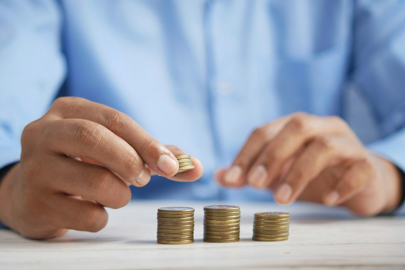 Mãos organizando pilhas crescentes de moedas — consórcio como investimento